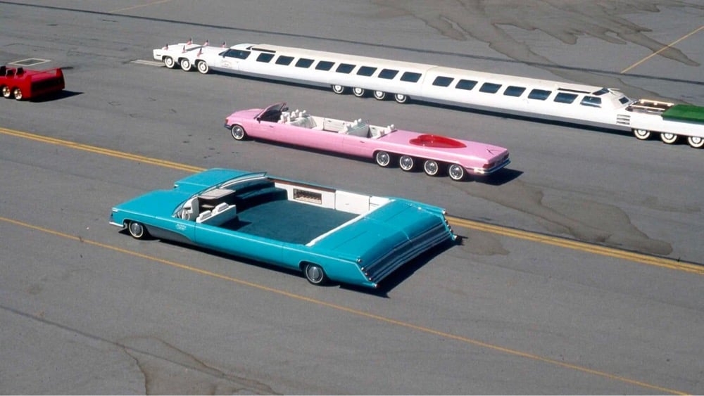 a double-wide blue Cadillac, a long pink convertible, and a comically long limousine