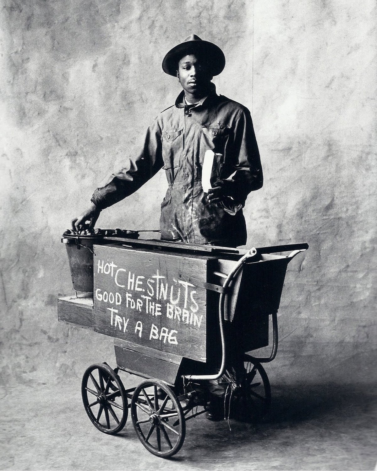 black & white photo of a man selling chestnuts from a cart