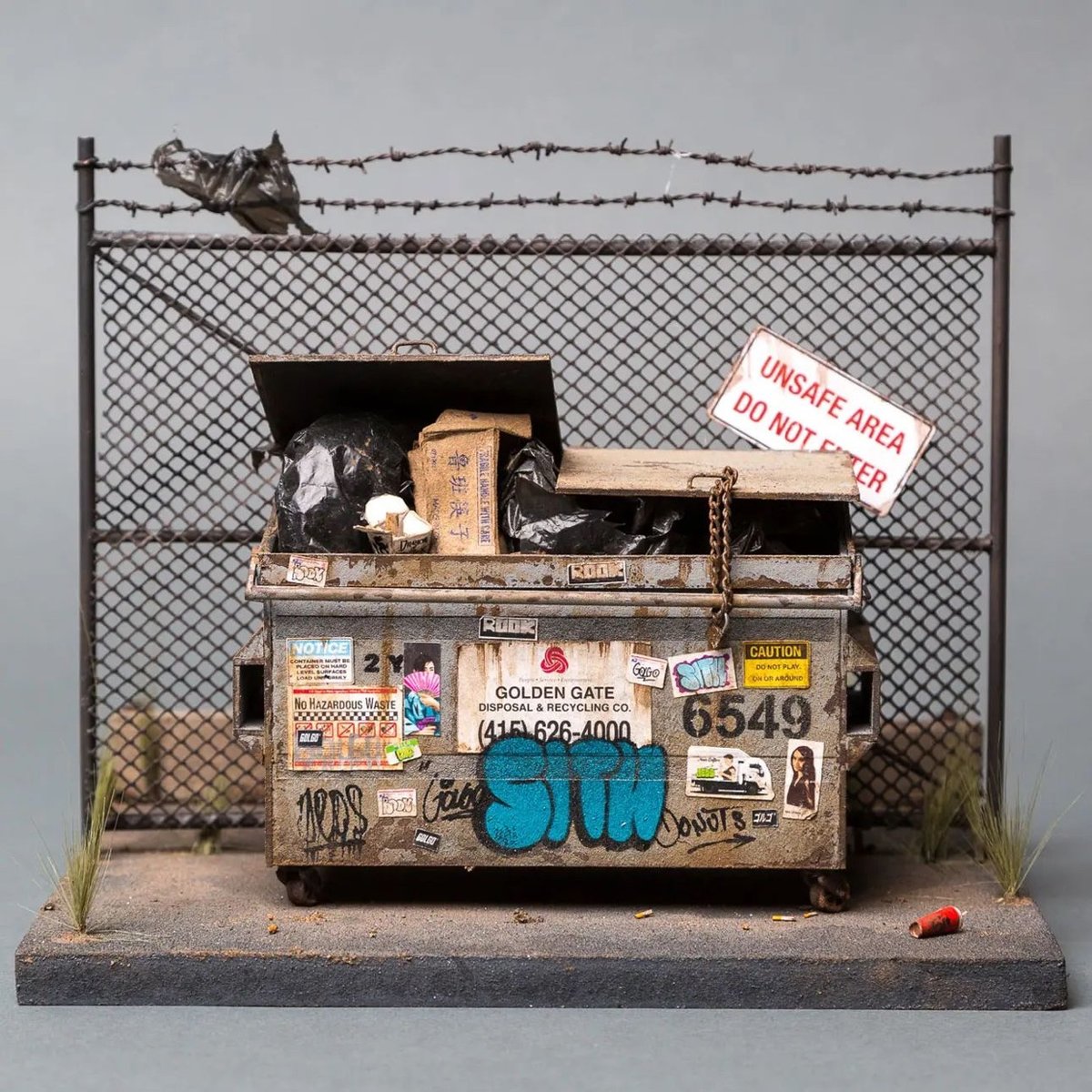 a miniature of a dumpster in front of a fence