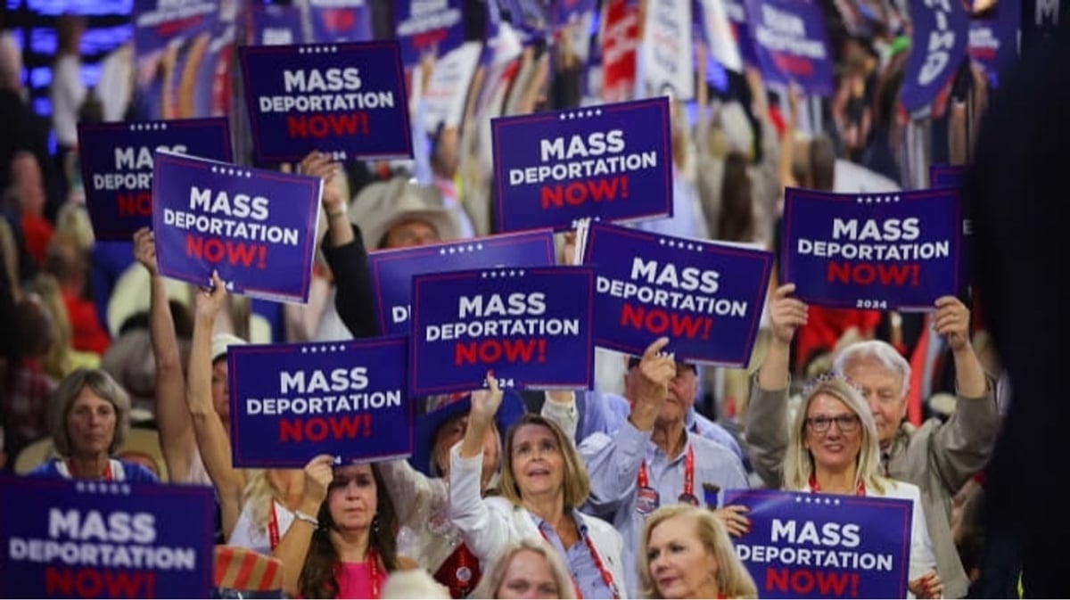 a sea of white people, mostly women, holding signs at the 2024 RNC that say 'mass deportations now!'