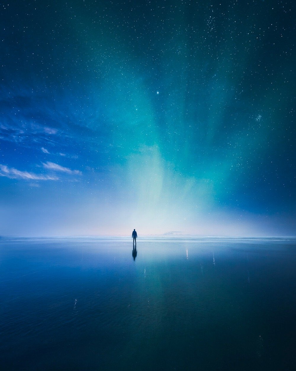 a man standing on a reflective surface under a brilliant blue night sky