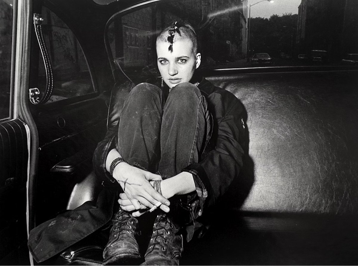a young woman with a mohawk sitting in the back of a taxi