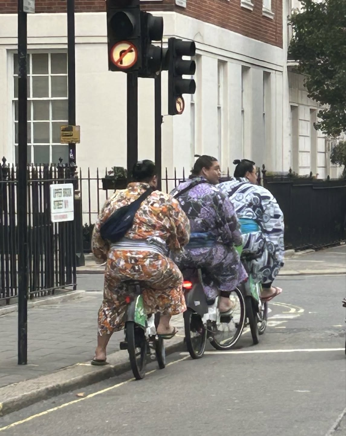 group of sumo wrestlers riding bikes in London