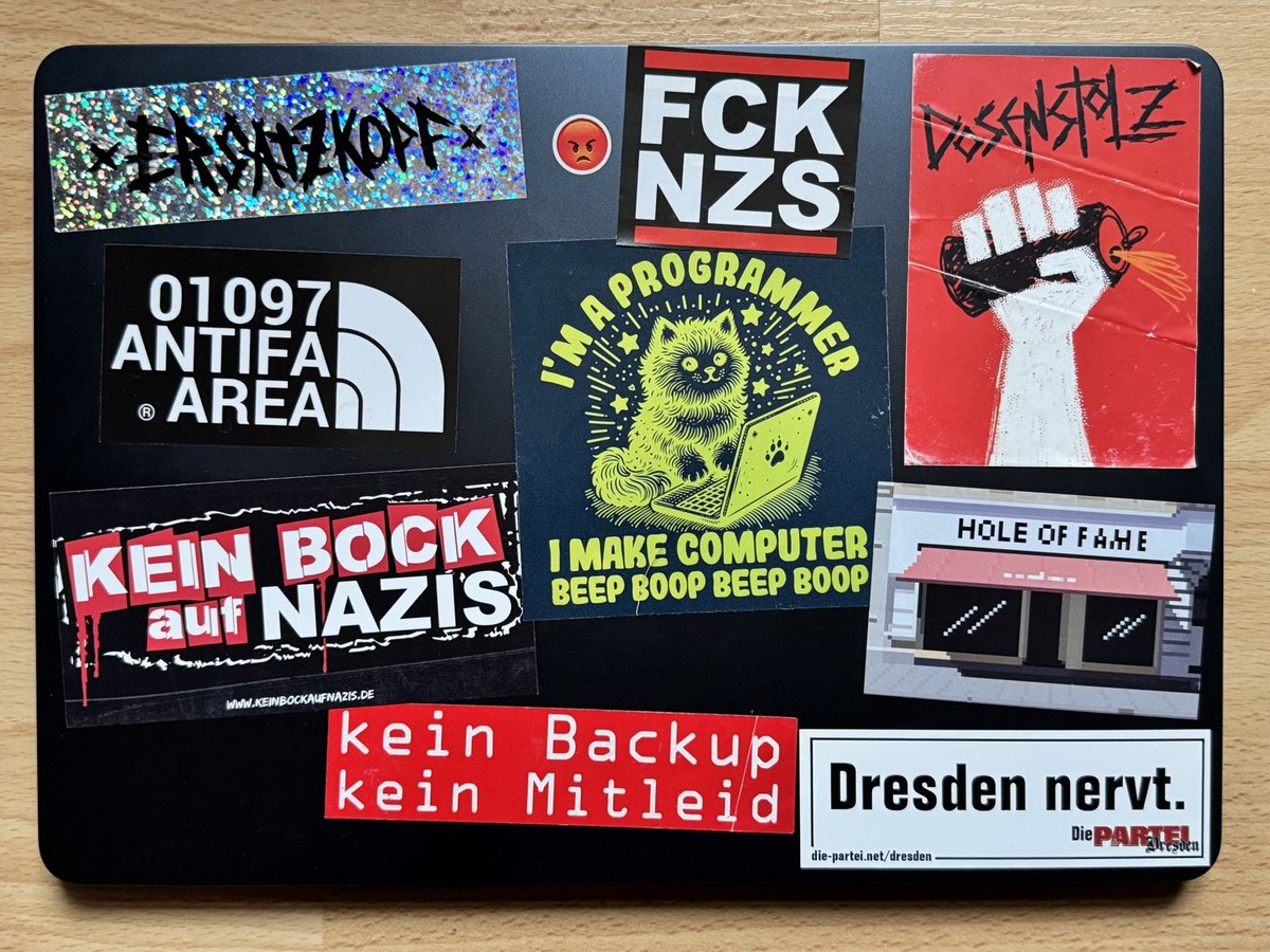 Zwarte laptop bedekt met anti-nazi- en antifascistische stickers, waaronder slogans, bandlogo's en politieke boodschappen.