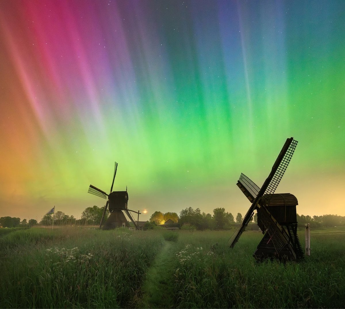 a photo of the aurora borealis above windmills