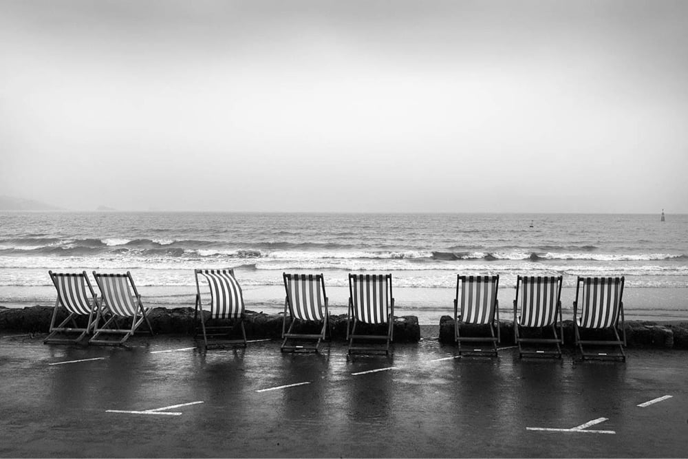 a row of deck chairs sit empty in front of the ocean