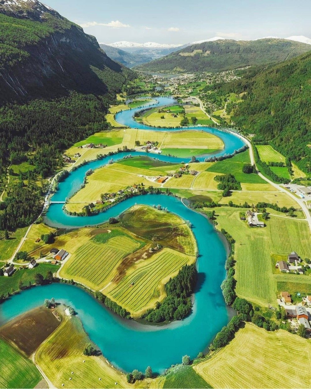 a vivid blue river meanders through a green valley