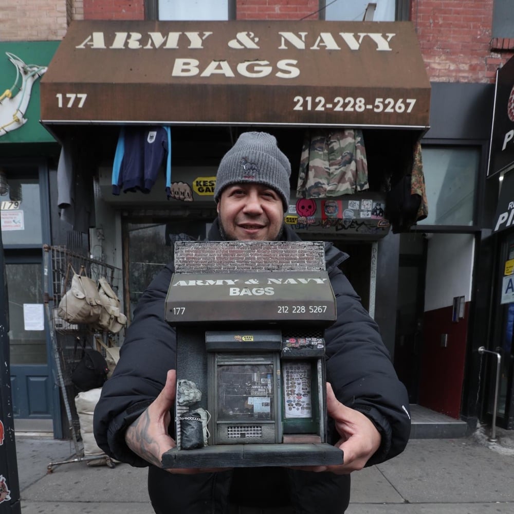 Danny Cortes holds a miniature of an NYC store in front of the store