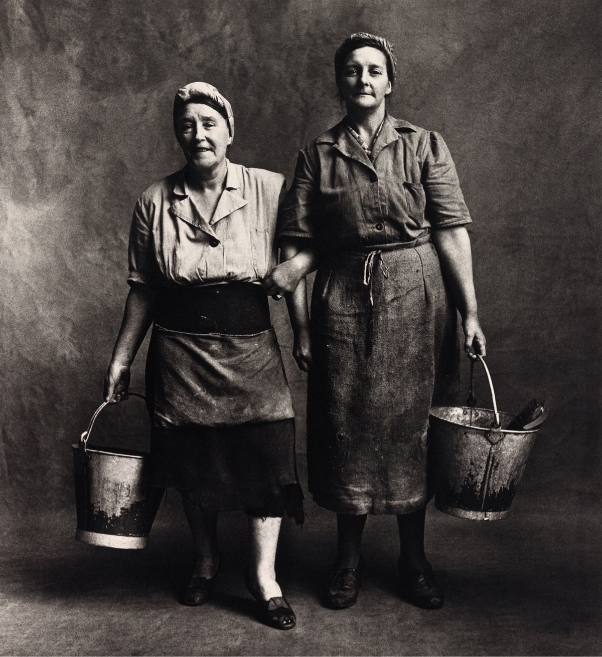 black & white photo of two tradewomen carrying buckets