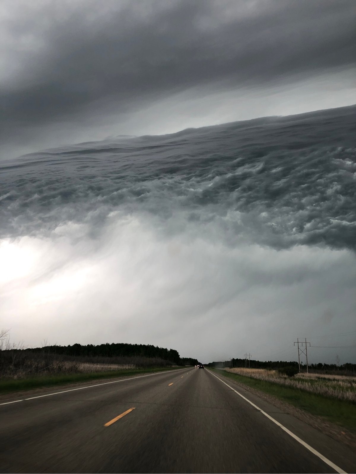 a bank of clouds over the road looks like a rising ocean tide