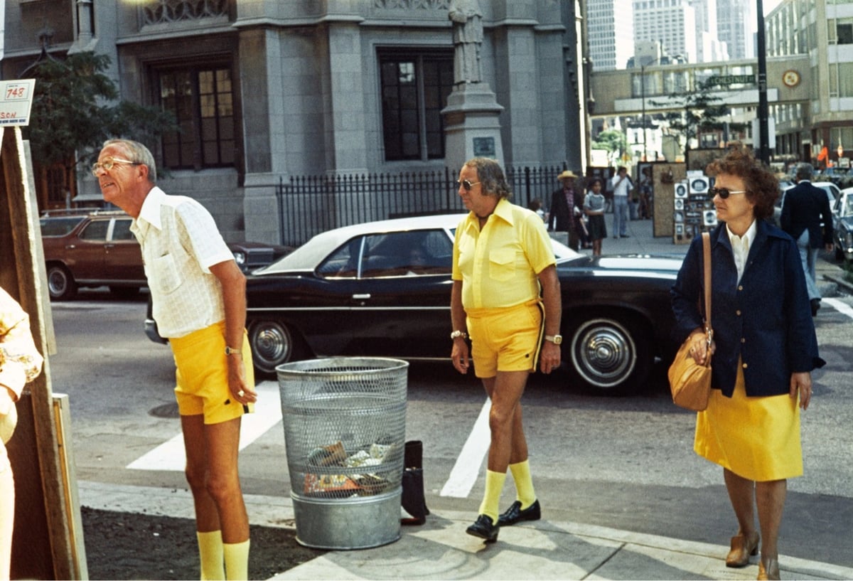 photo of three people on a street corner, all wearing the color yellow