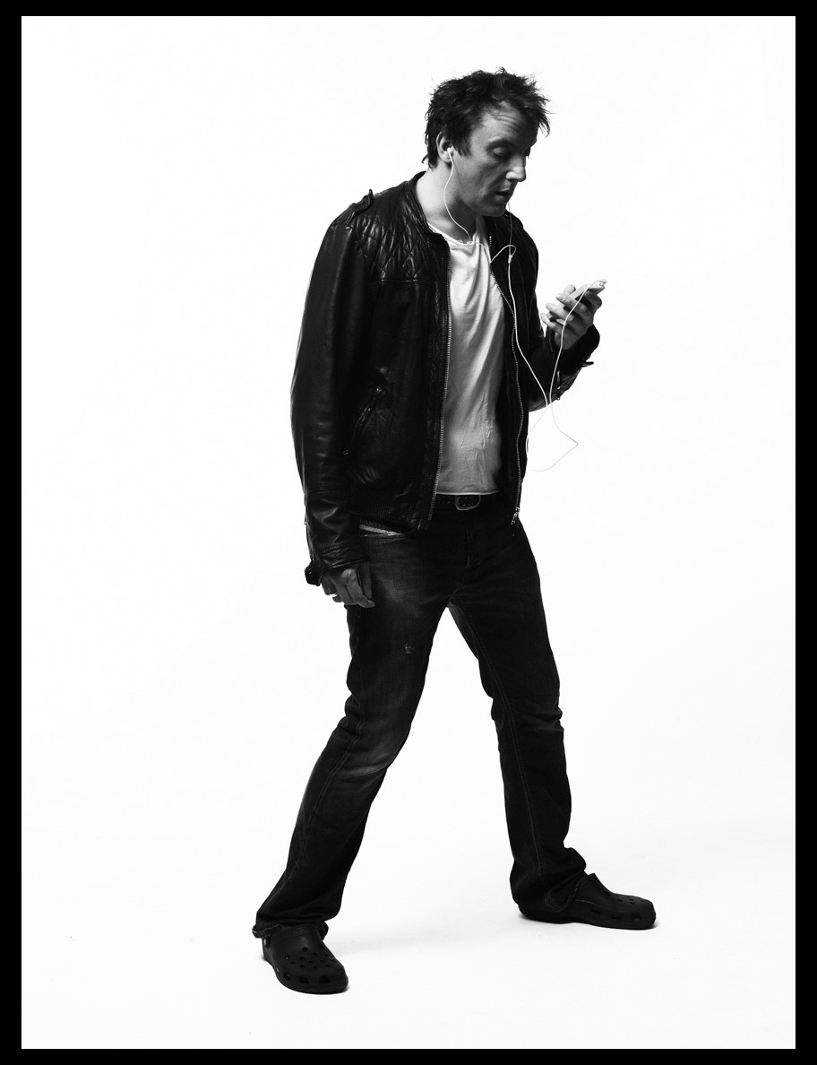 black and white photo of Peter Serafinowicz listening to an iPod on his white headphones