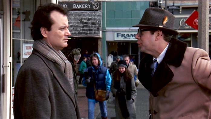Weatherman Phil Connors and would-be-acquaintance Ned Ryerson smile grimly at each other in a still from Groundhog Day