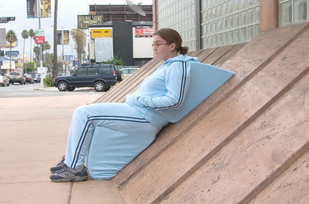 a woman sitting against a slanted wall