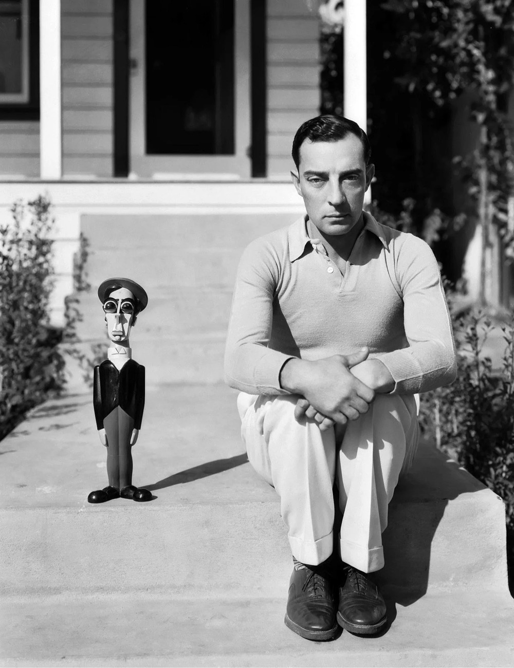 actor Buster Keaton sitting next to a Buster Keaton doll