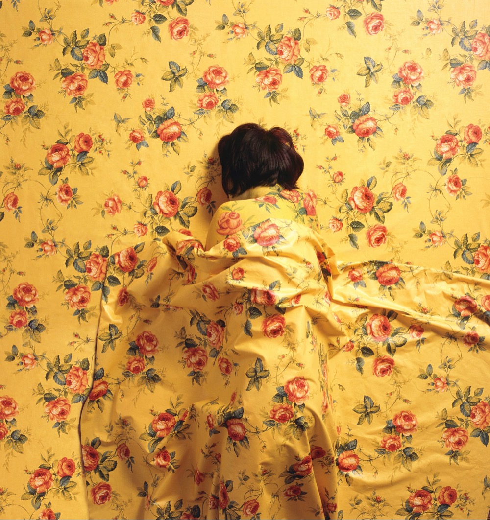 a woman camouflaged to blend into a patterned wall