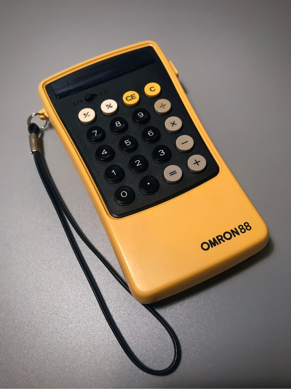 a vintage yellow calculator with a carrying strap