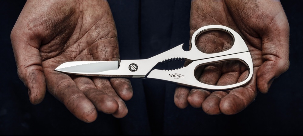 hands holding a pair of silver kitchen scissors