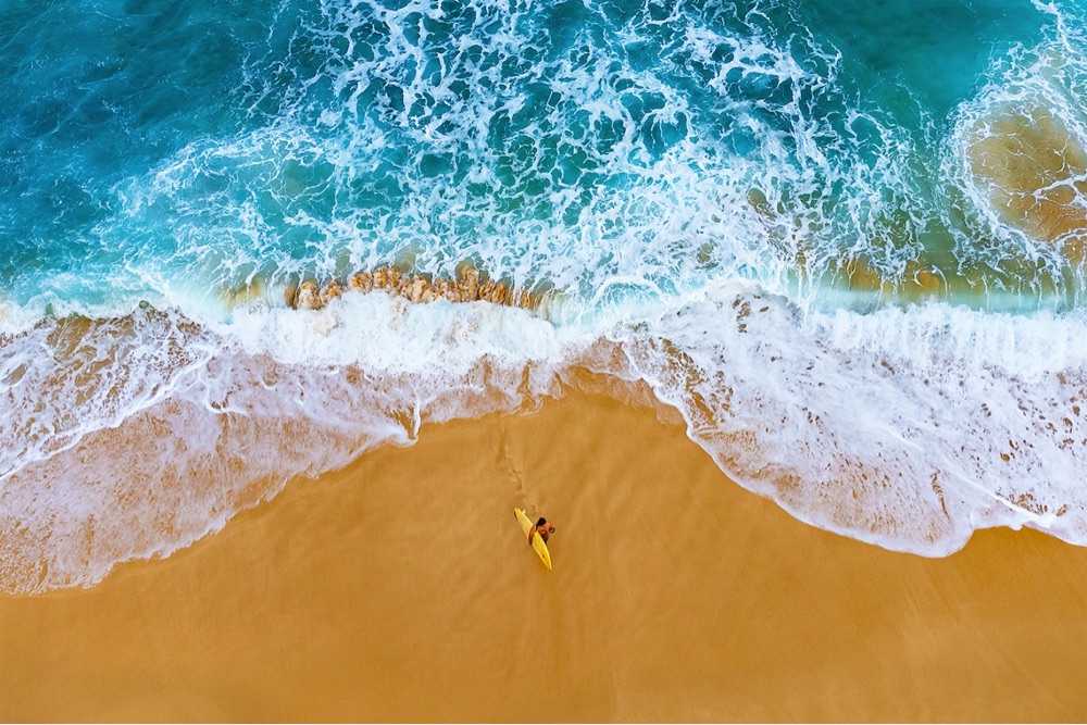 aerial photo of a surfer and crashing waves