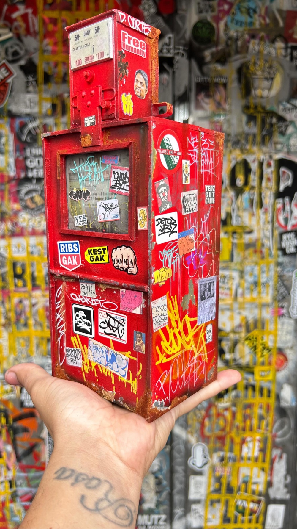 miniature newspaper box covered with stickers and grafitti