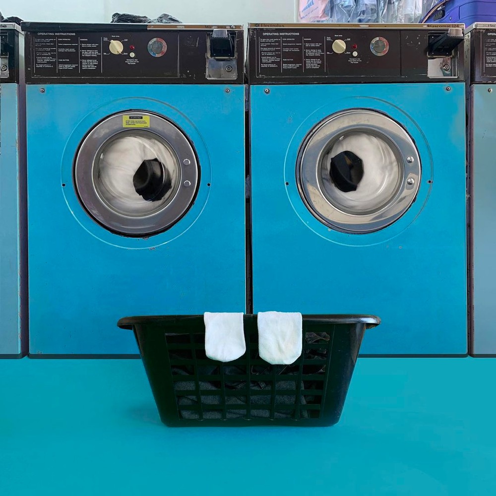 two washing machines and socks hanging on a laundry basket that look like a face