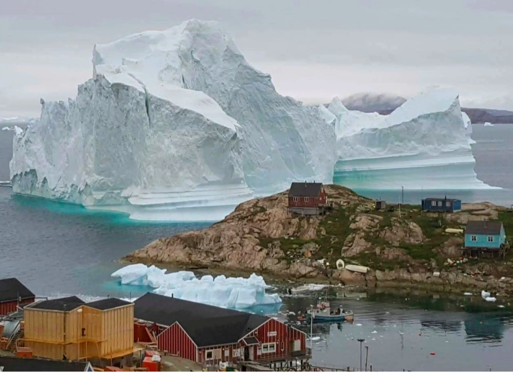 a massive icreberg threatens a Greenland village