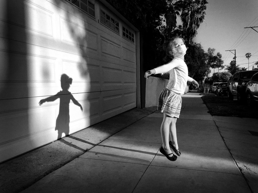 a girl jumps in the air, with her shadow behind her