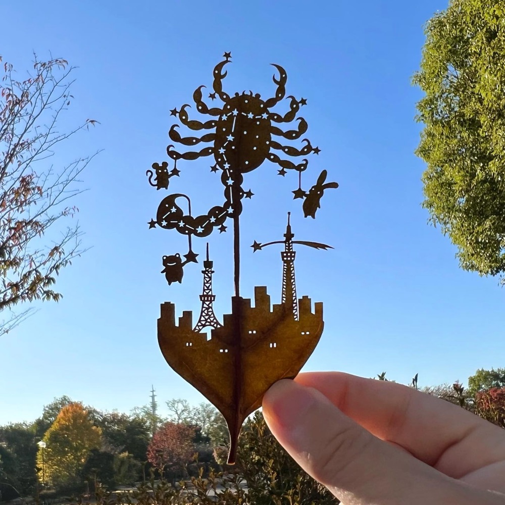 leaf cutout art of crab constellation in the sky over a city