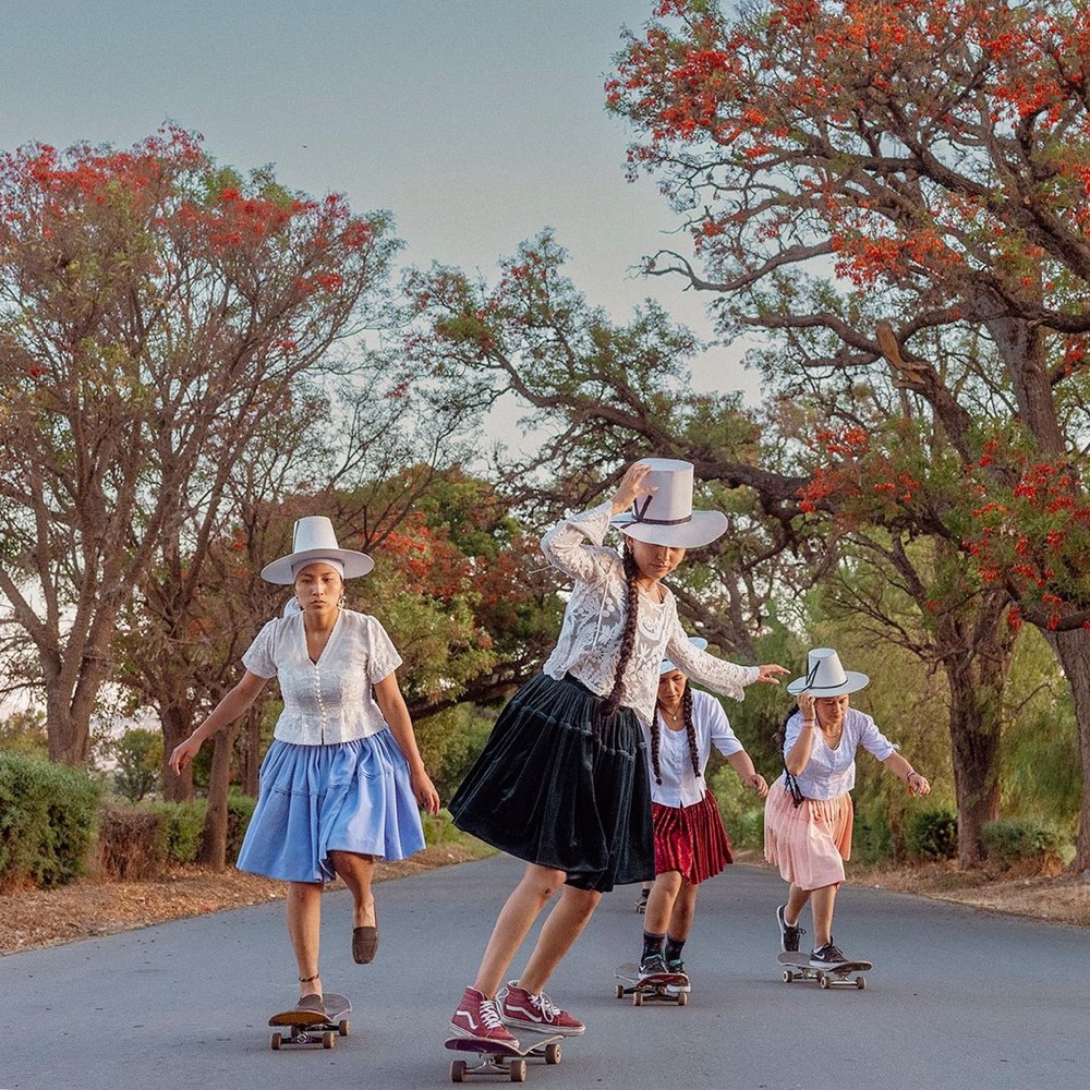 a group of Bolivian women skateboard in traditional clothing