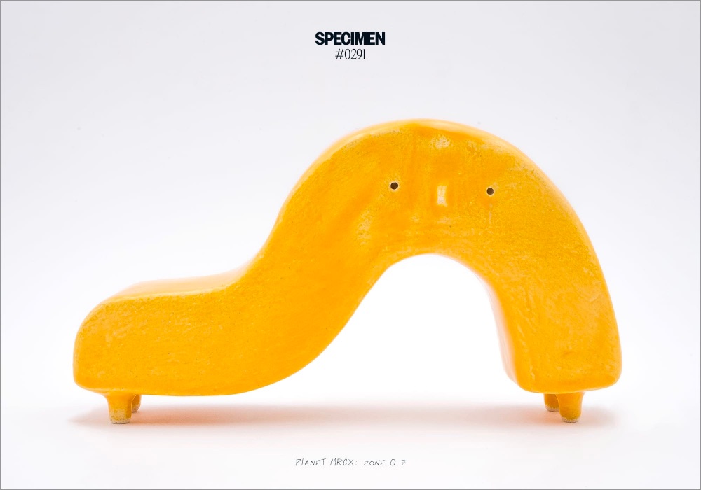 a yellow ceramic alien shaped like a question mark
