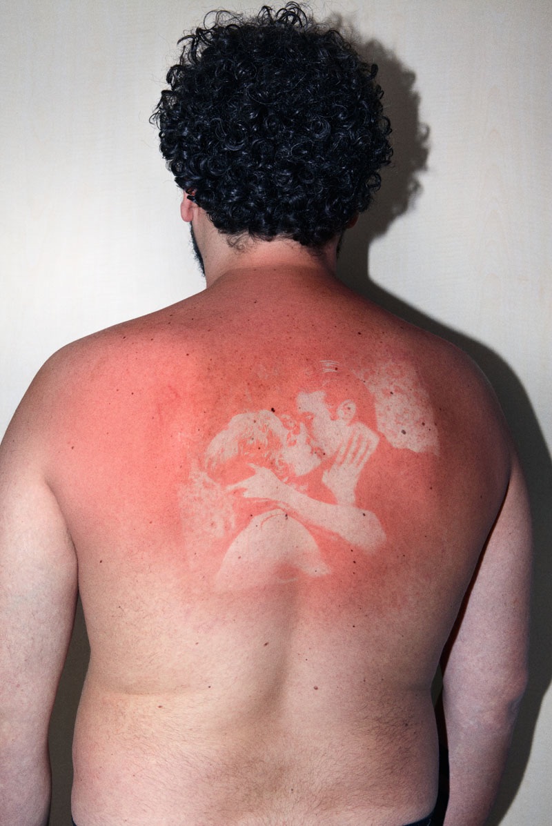 a person's back with a photo 'sunburnt' onto it with a UV light