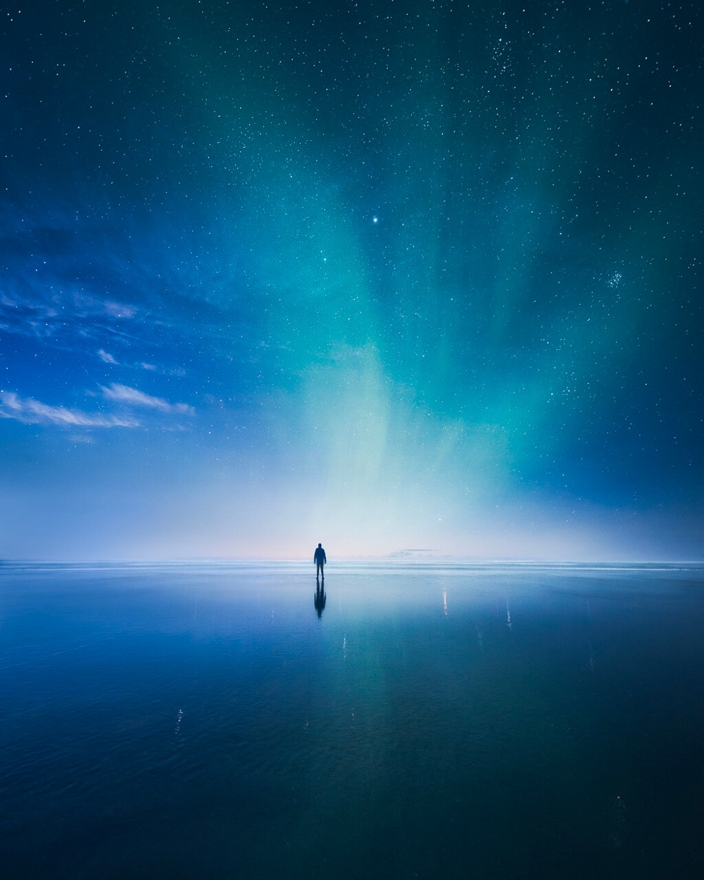 a man standing on a reflective surface under a brilliant blue night sky