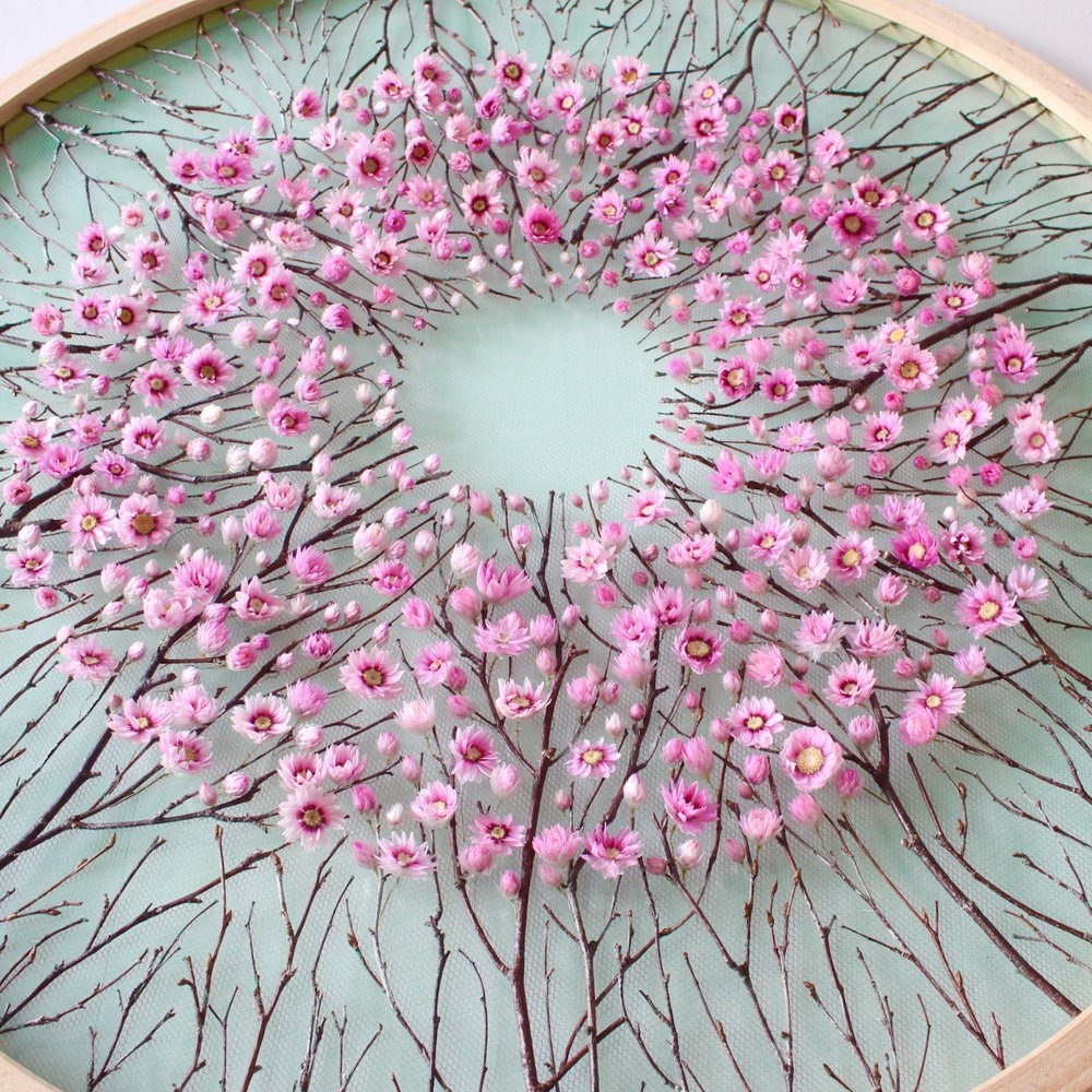 flowers and branches arrnaged in a circular pattern on an embroidery hoop