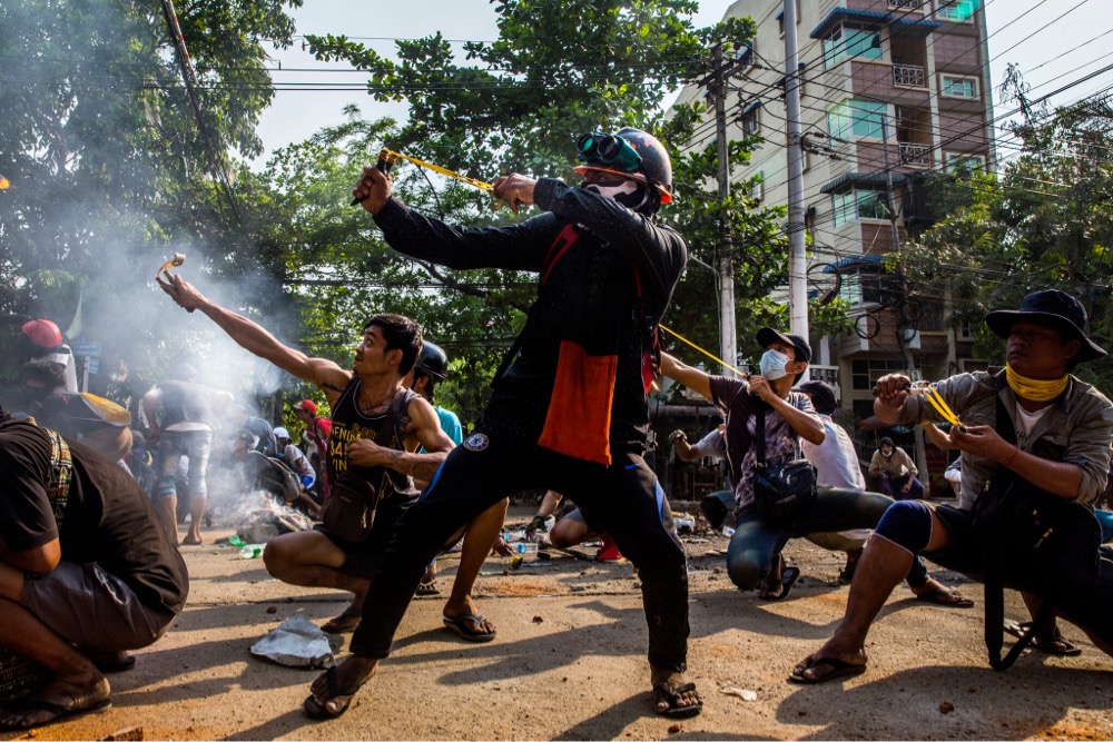 citizens protesting the coup in Myanmar firing slingshots