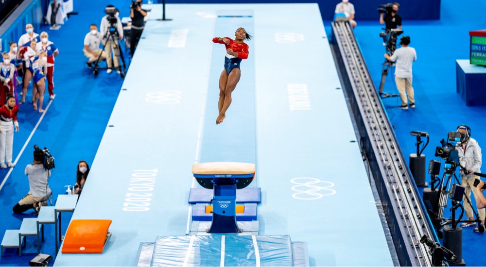 Simone Biles flying high in the air above the vault