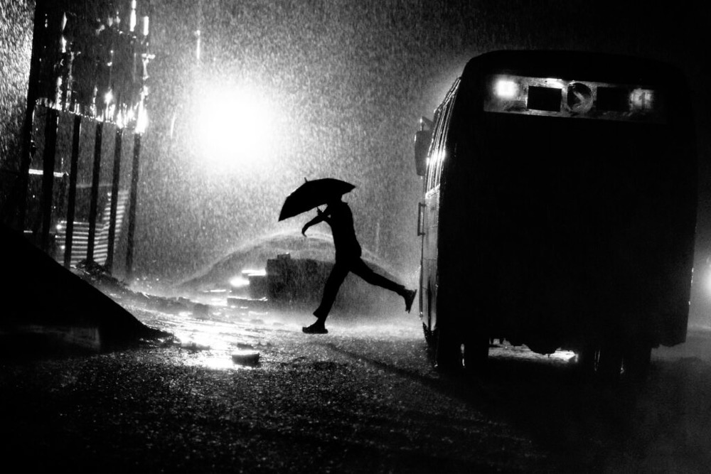 a man steps off of a bus holding an umbrella
