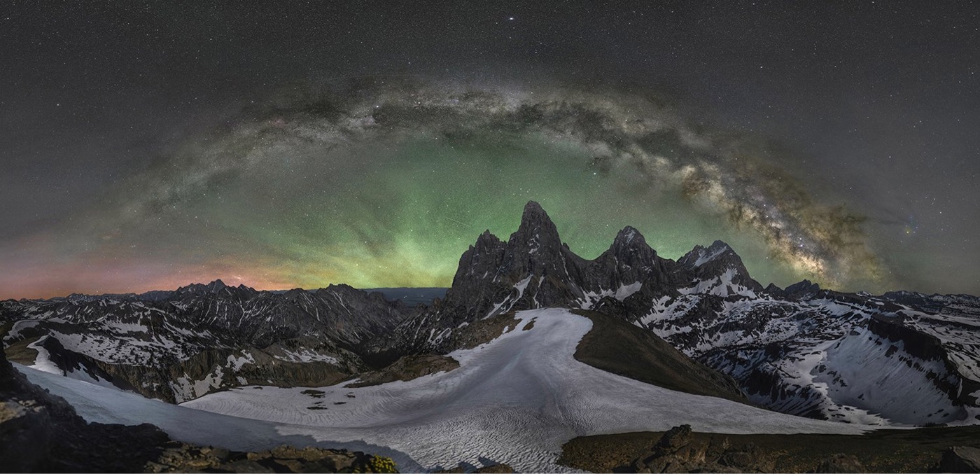 the Milky Way stretches above snowy mountains